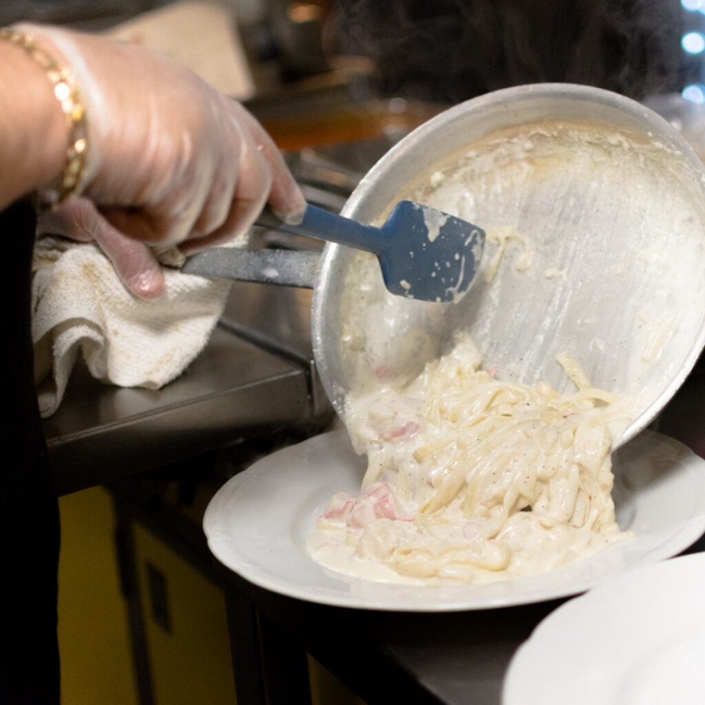 Chef plating pasta with Alfredo sauce at Angelo's Restaurant