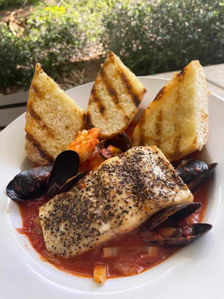 Grilled Salman and Mussels in a red sauce with white toast points on a white plate from Bogey's bar and grill