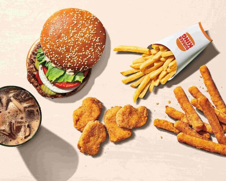 Burger King Whopper Jr. with bun sliding off the burger to show patty and condiments, plus four chicken nuggets, a box of french fries, seven cheese sticks and a cup of cola