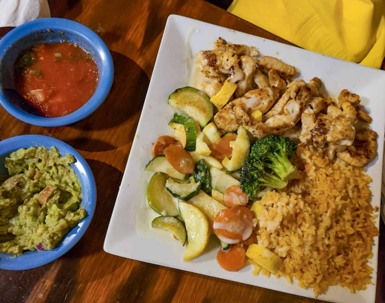 Compas Cancun Plate with grilled chicken strips, refried rice, sauteed summer vegetables and sides of salsa and guacamole