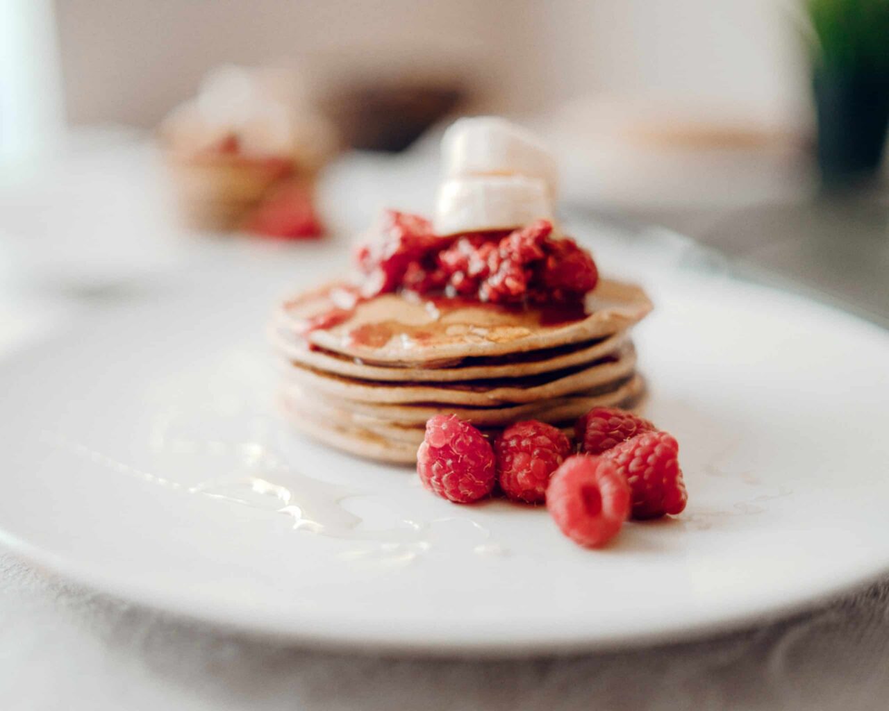 IHOP stack of pancakes topped with raspberries on a white plate