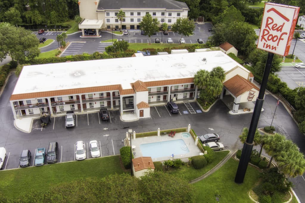 Aerial Shot of two-story Red Roof Inn building in Kingsland taken from the west with outdoor swimming pool and highway sign in foreground