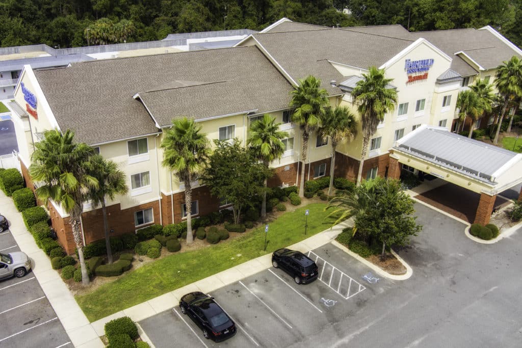 Aerial shot of Fairfield Inn & Suites by Marriott in Kingsland Georgia with parking lot in foreground and portico and front entrance on the right of the photo