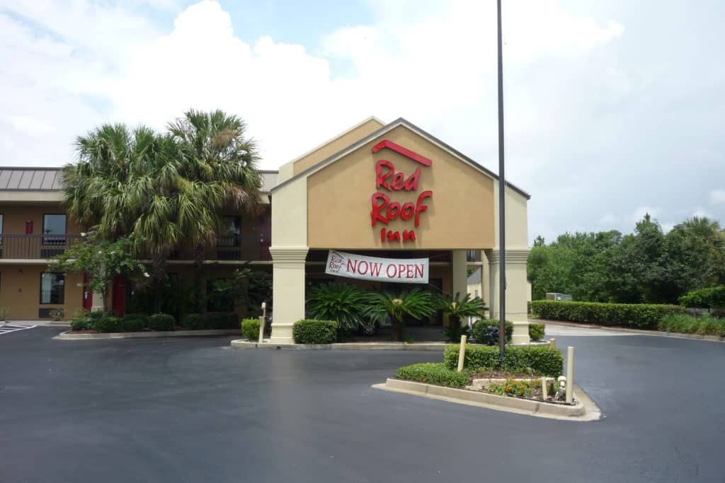 Red Roof Inn Kingsland Exterior shot of driveway, portico, and front entrance with a sign that reads "NOW OPEN"