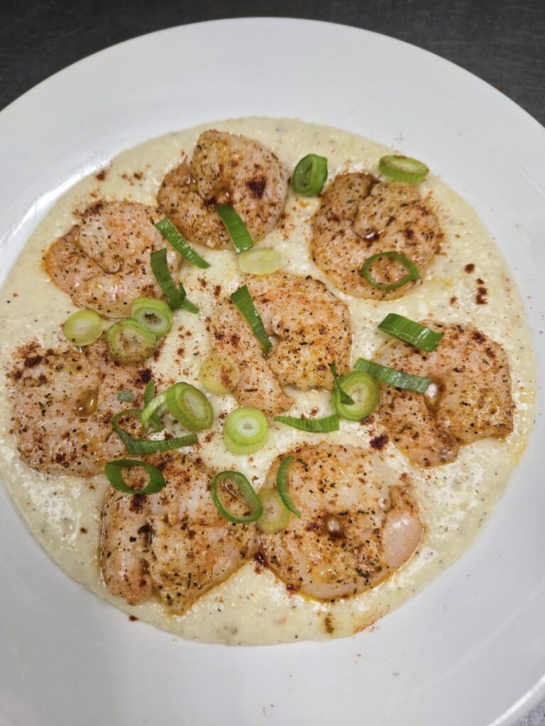 Plate of seven blackened shrimp on a bed of Gouda grits garnished with sliced spring onion