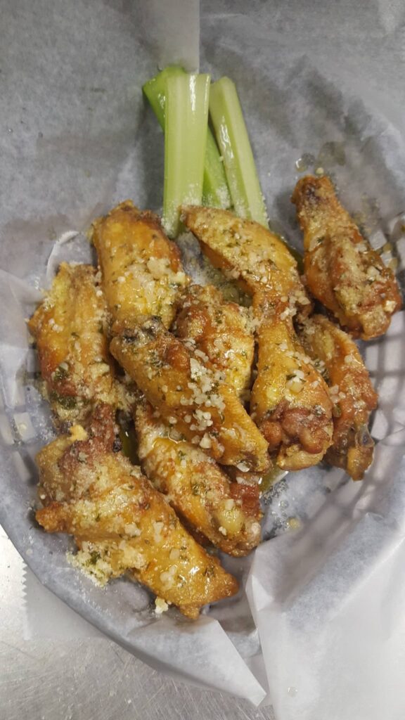 Plate of eight barbequed chicken wings with celery stick garnish