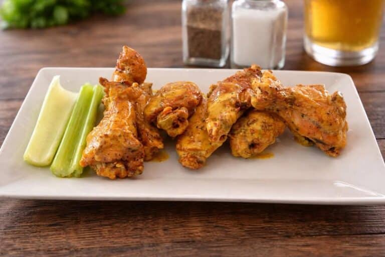 Six chicken wings and two celery stalks on a plate