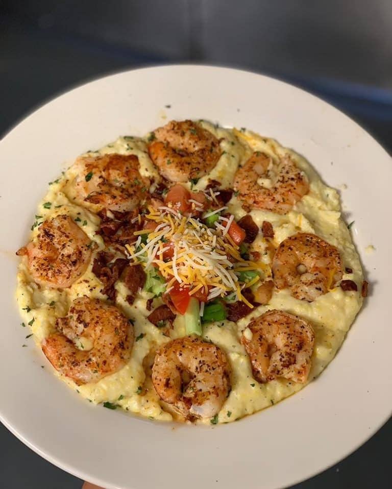 Eight blackened and grilled shrimp on a bed of cheesy grits topped with bacon bits and shredded cheese from St. Marys Seafood and More