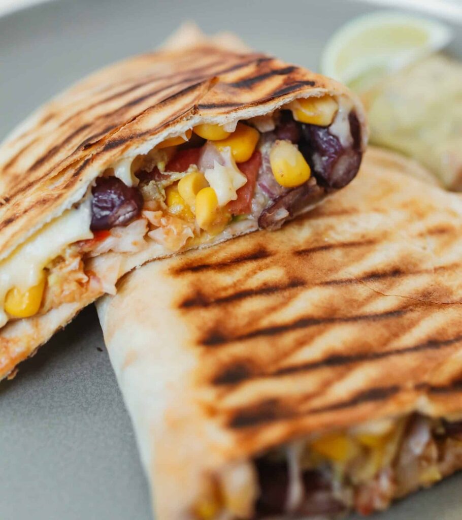 pressed sandwish with cheese, beans, and corn on a flour torilla