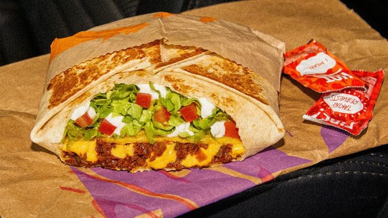 Taco Bell Crunch Wrap Supreme on Taco Bell branded wrapper with two packets of sauce on the side