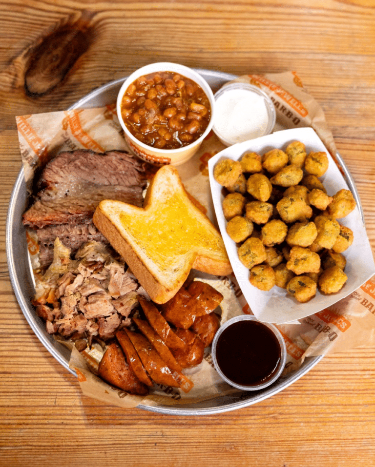 Barbeque plate with kielbasa, pulled pork, ribs, and sides of baked beans and fried okra