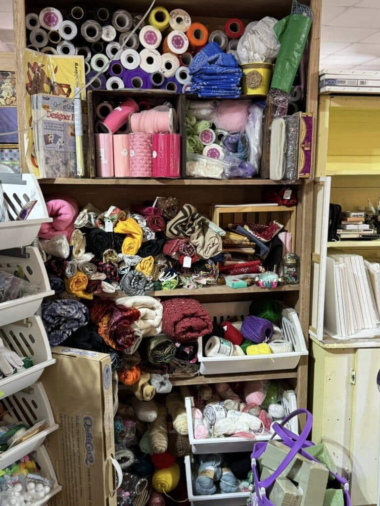 wooden shelf display of fabric, ribbon and thread for crafting