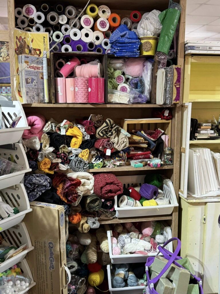 wooden shelf display of fabric, ribbon and thread for crafting