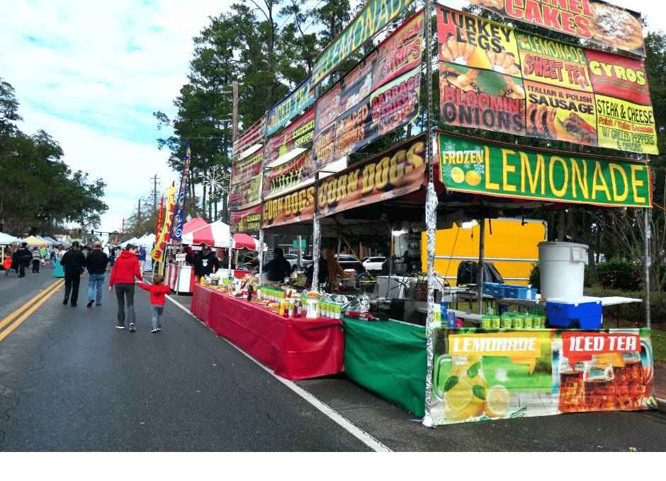 Family enjoys the festival festivities as they walk down a street next to food and craft vendors.
