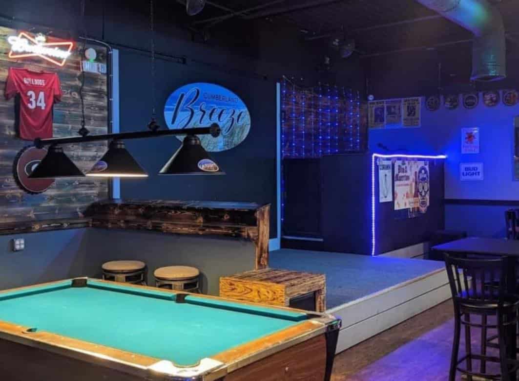 Pool table in a bar with a booth in the background