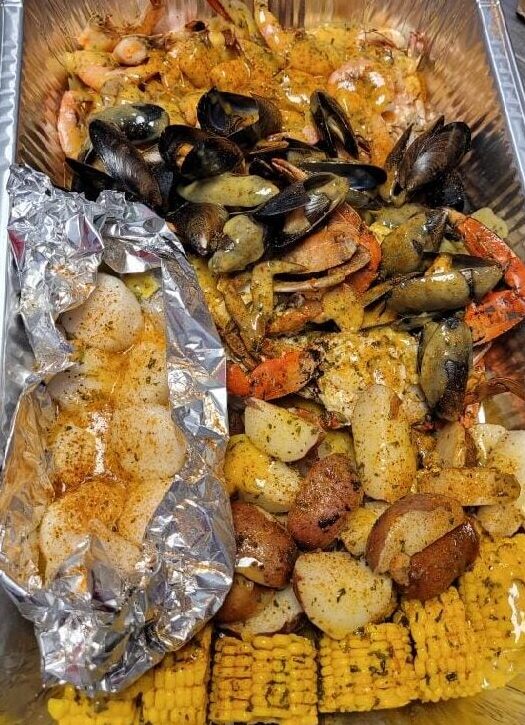 Low country boil with corn on the cob, potatoes, crab legs, mussels, shrimp, and scallops in an aluminum pan from M&A's Seafood