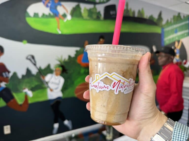 iced coffee drink in clear plastic Hometown Nutrition branded cup with lid and a red straw