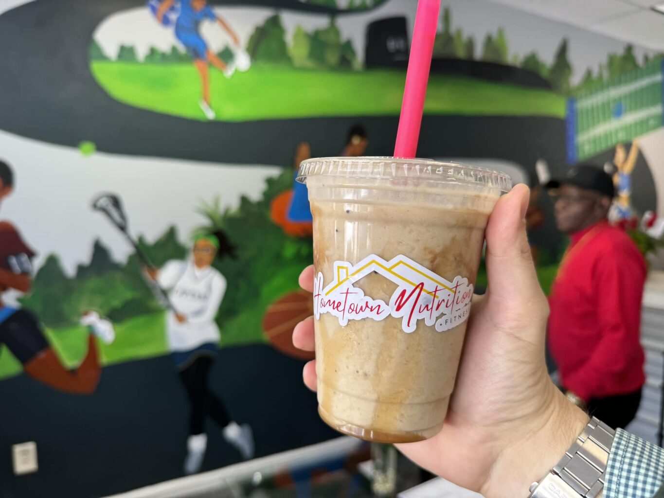 iced coffee drink in clear plastic Hometown Nutrition branded cup with lid and a red straw