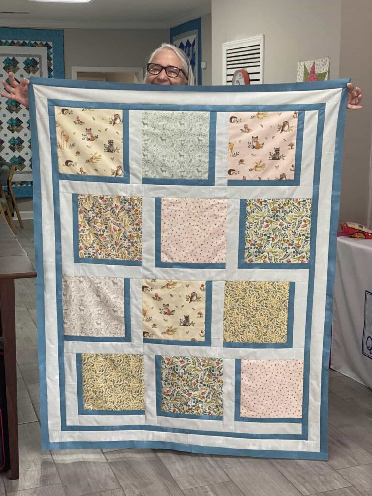 Lady holding up a patchwork quilt
