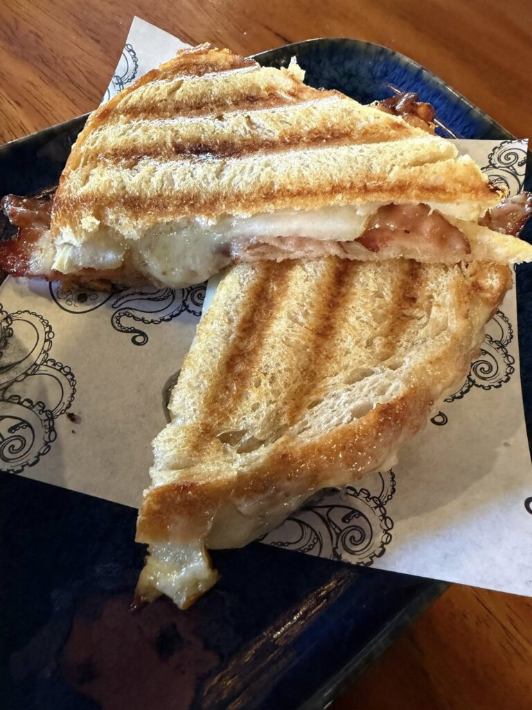 Toasted ham, fig, and cheese sandwich cut in half on a small plate