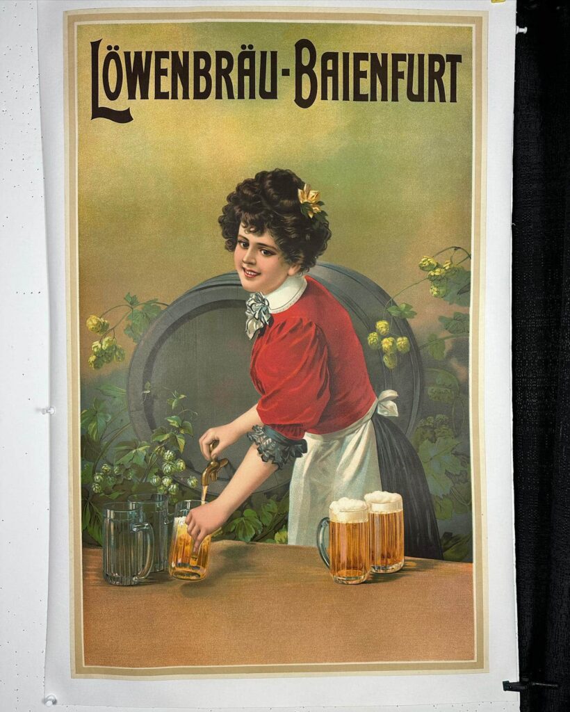 Antique French Poster for Lowenbrau beer picturing a brunette barmaid wearing a red shirt with a white collar and a white apron