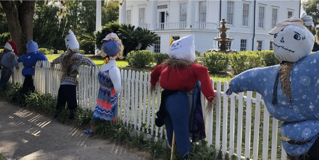 A series of scarecrows tied to a white picket fence at Orange Hall in St. Marys, Georgia