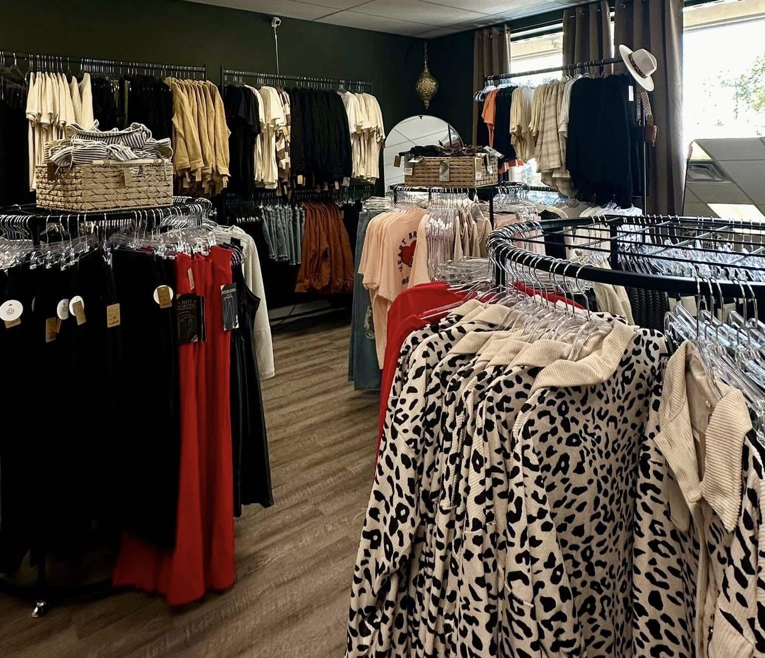 Circular racks of clothing hanging from clear plastic hangers in a shop