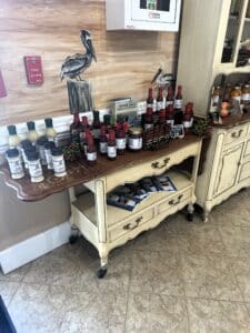 Display of Kingsland Georgia branded BBQ and hot sauces, vidalia onion dressing and salt, and Georgia cookbooks on a French provincial rolling cart