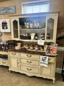 Canned peaches, baking mixes, and olive oils displayed on a French provincial style hutch