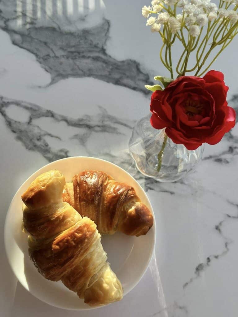 Croissants on a plate and flowers in a vase on a table at Awaken Coffee Company