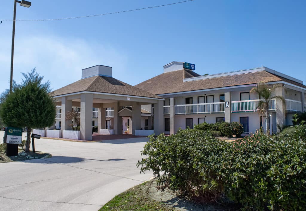 Exterior of driveway, portico, and front entrance of Quality Inn in Kingsland, Georgia, on a sunny day
