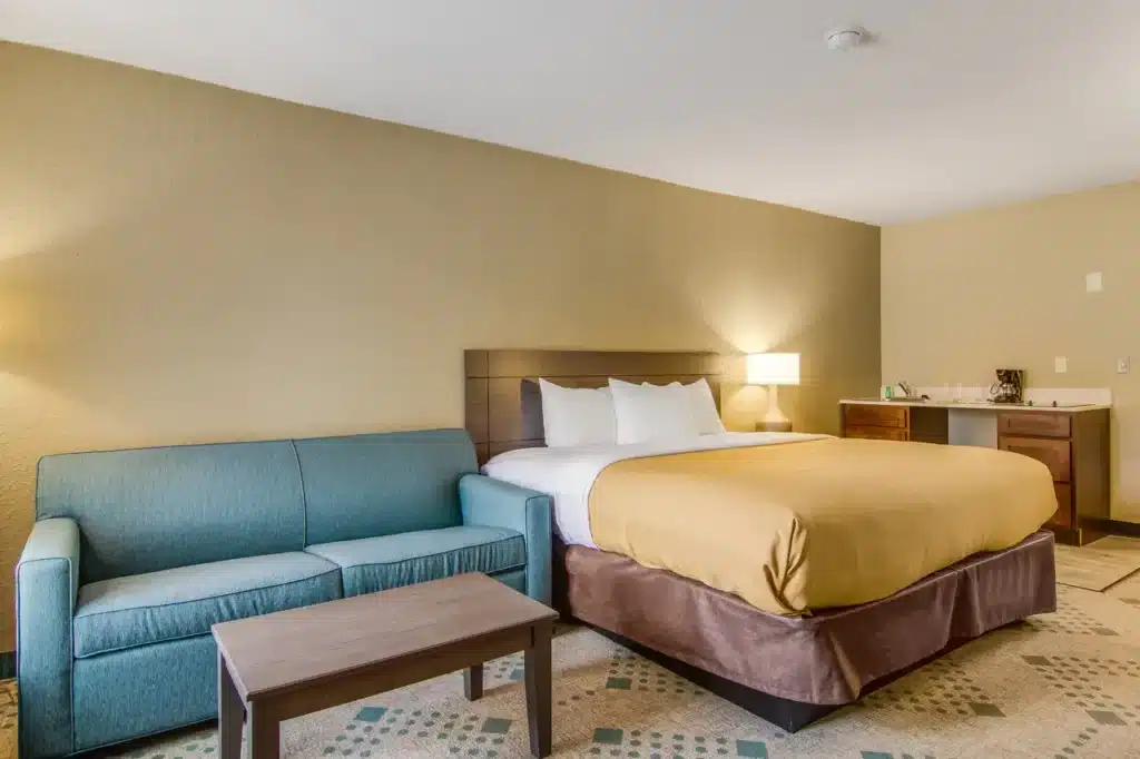 Suburban Studios Guest Suite with Queen Bed Sofa Coffee Table Bar Sink from website 03-19-2026