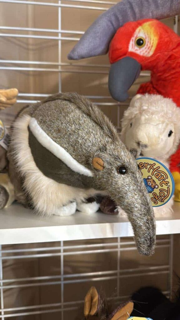 Stuffed anteater, lamb, and parrot dolls on a shelf