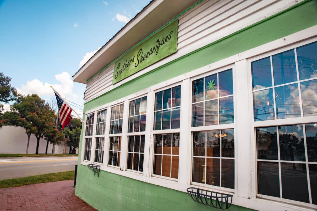 Exterior of antique shop painted light green with white trim and with seven side-by-side paned windows in Kingsland Georgia