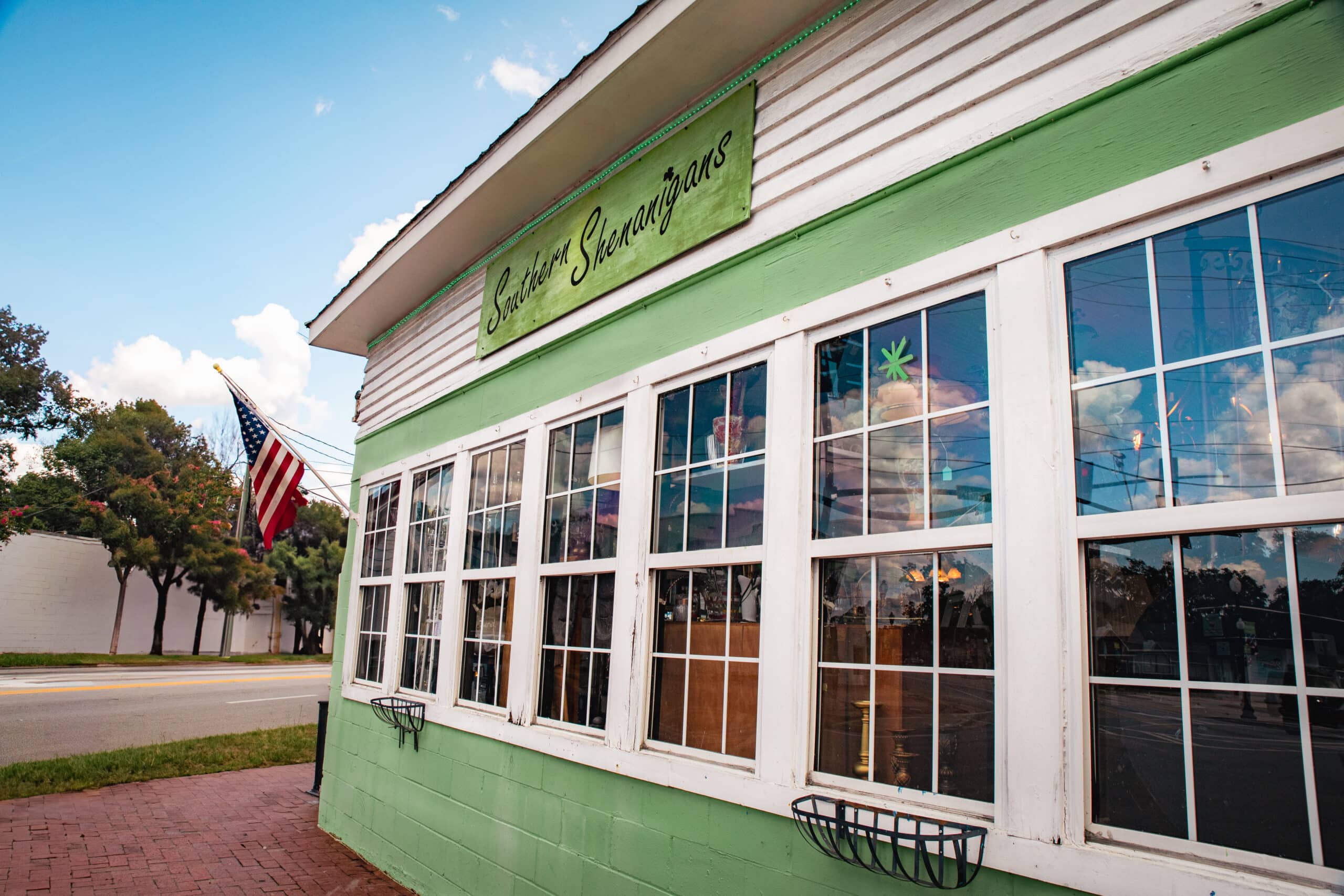 Exterior of antique shop painted light green with white trim and with seven side-by-side paned windows in Kingsland Georgia
