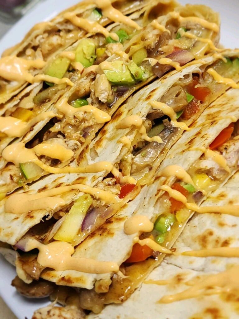 Stack of chicken Mediterranean quesadilla portions drizzled with aoli sauce