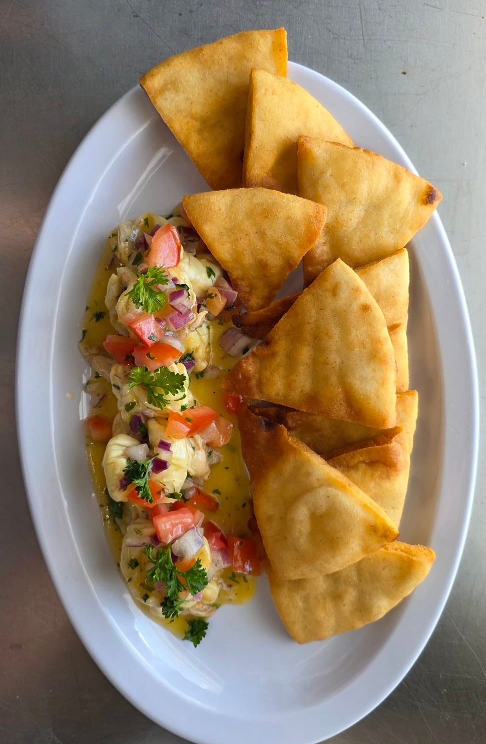 Shrimp Ceviche and pita triangles on a white oval plate.