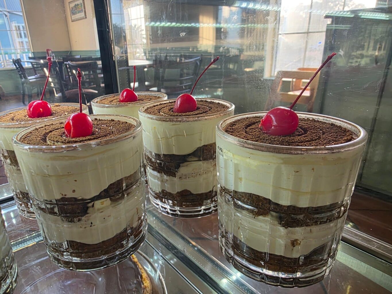 Four tiramisu desserts topped with cherries in double old-fashioned glasses on display at the restaurant