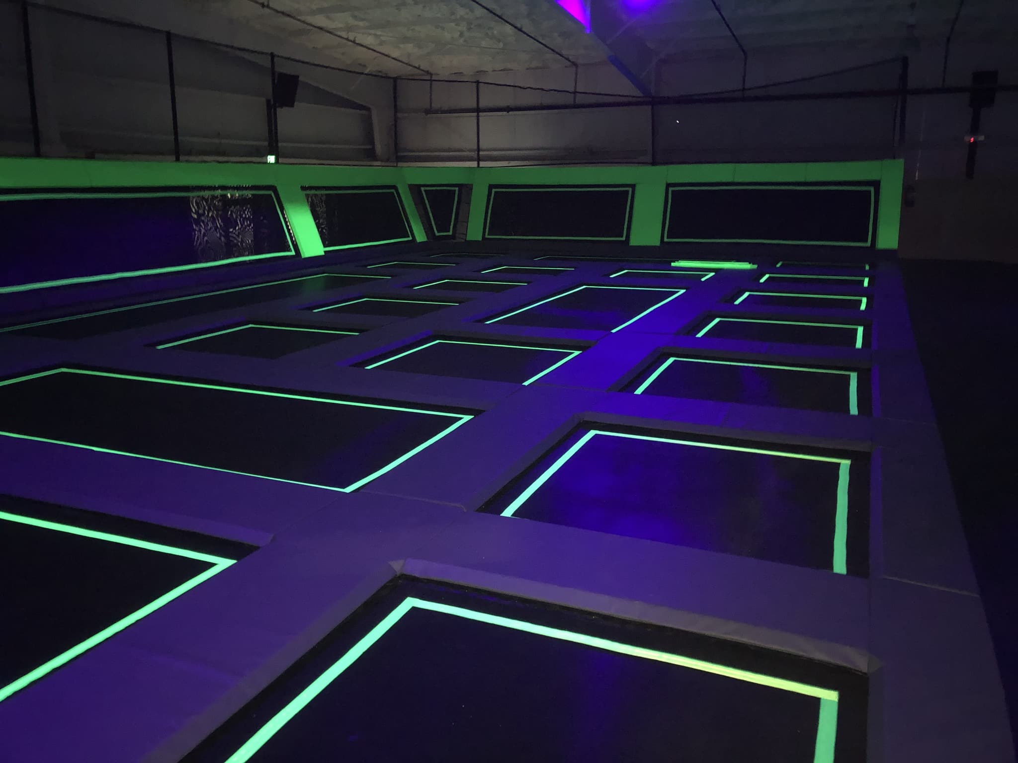 Black light lit indoor trampolines glowing in neon green and purple