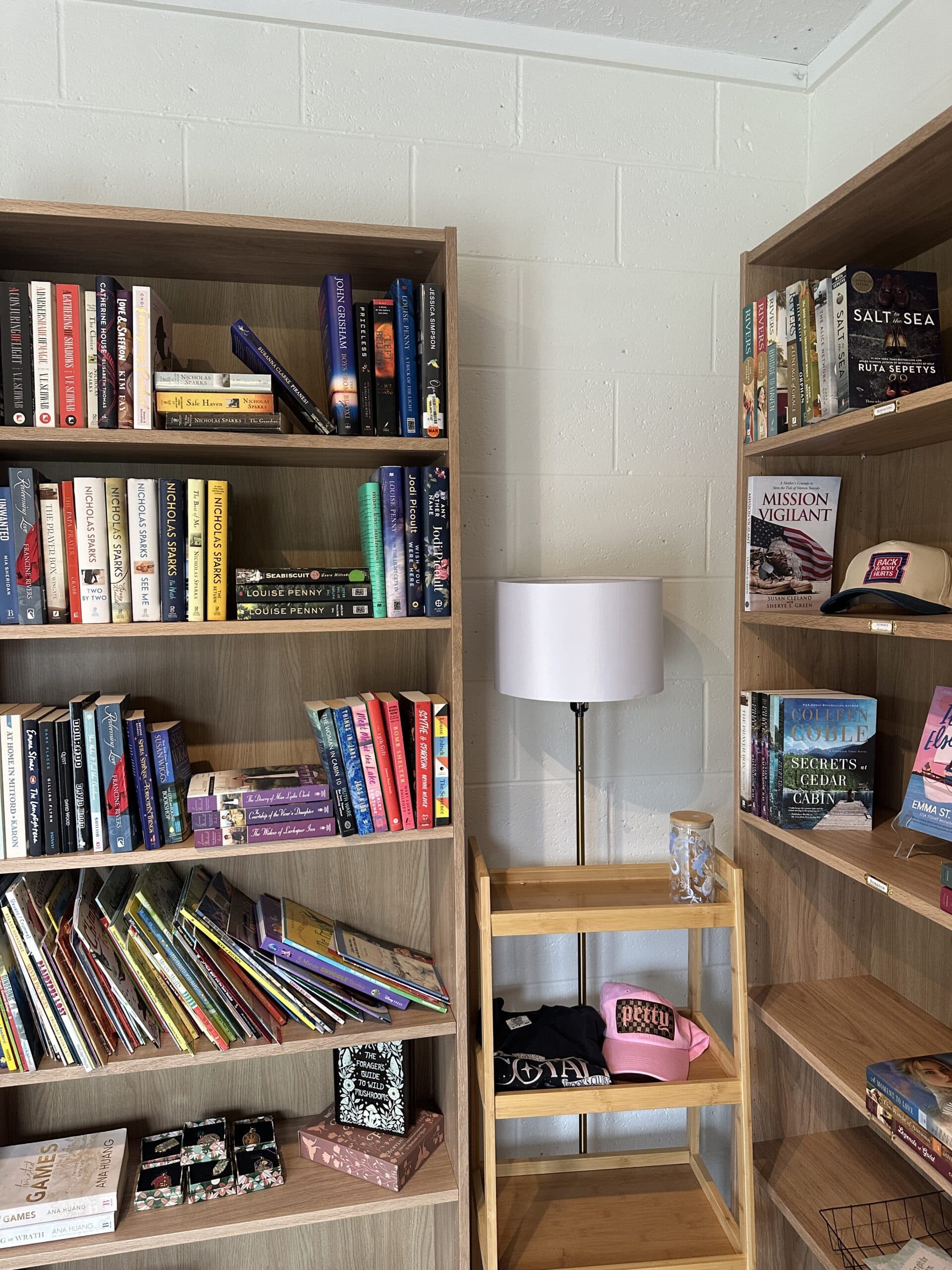 Interior corner of book shop with bookshelves on both walls and a lamp with a white shade