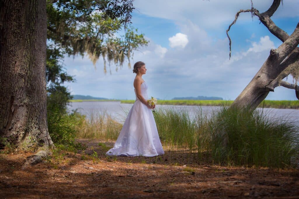 A bride stands next to a marsh area at Honey Creek