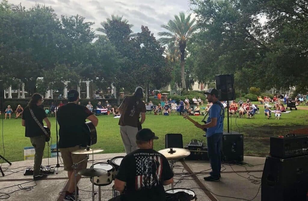 whiskey heart band playing at the St. Marys Waterfront Pavilion in July 2024, image shot from back so you can see audience on the green lawn in the background.