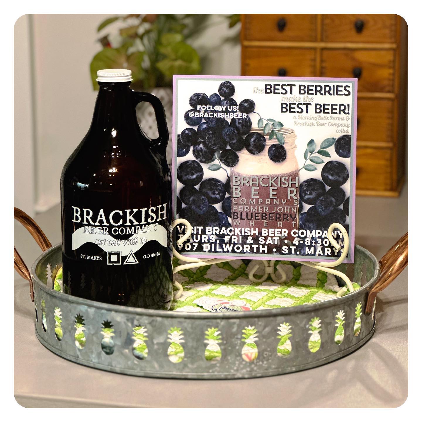 Growler bottle labeled Brackish Beer Company Get Lost With Us St. Marys Georgia with a small sign sitting on a metal tray