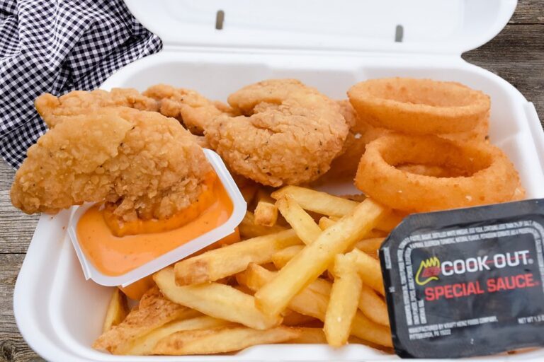 Fried Shrimp, onion rings, fries, and sauce in a Styrofoam container.