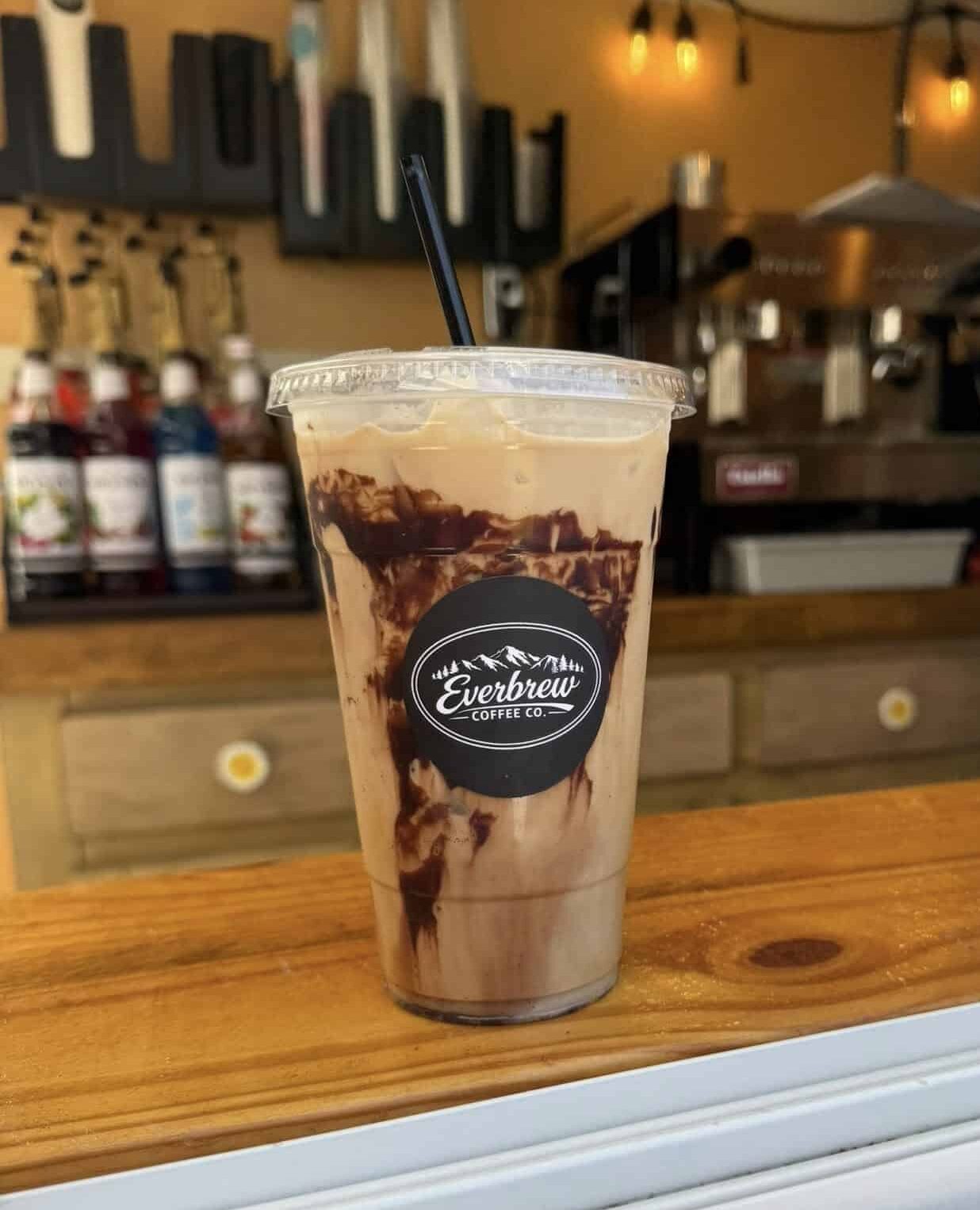 Ice White Mocha with Chocolate Walls in a clear plastic cup with a straw on a counter at Everbrew Coffee Co.