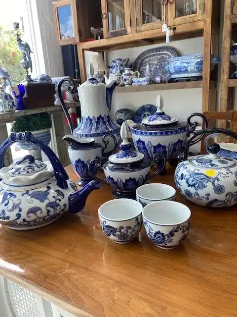 Display of blue and white Chinese tea sets on a wooden table.
