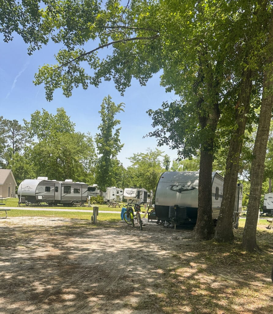 RVs and bicycles with a blue sky and shaded area at Walkabout RV Park
