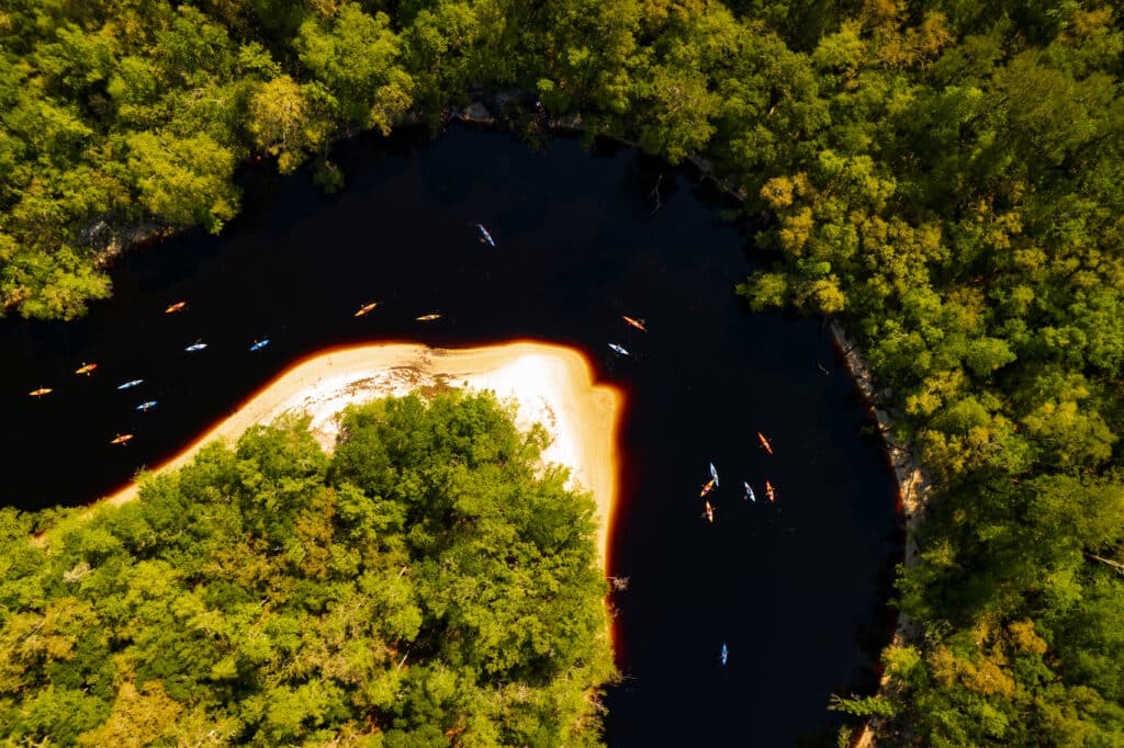 A group of Kayakers paddle along a riverbend on the St. Marys River
