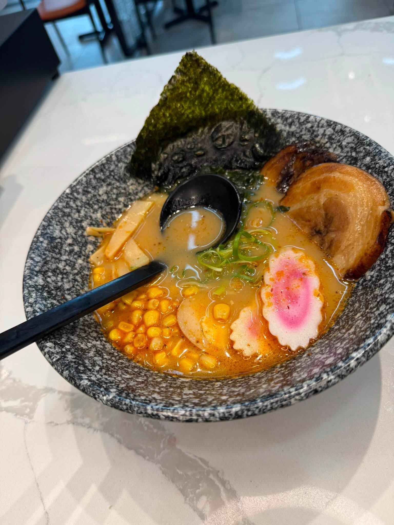Ramen in a blue soup bowl on a white table