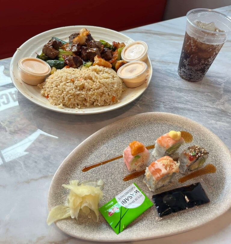 Combo lunch with a plate of hibachi steak, fried rice and a plate of four pieces of sushi with pickled ginger, packets of soy sauce and chop sticks, and a cup of cola